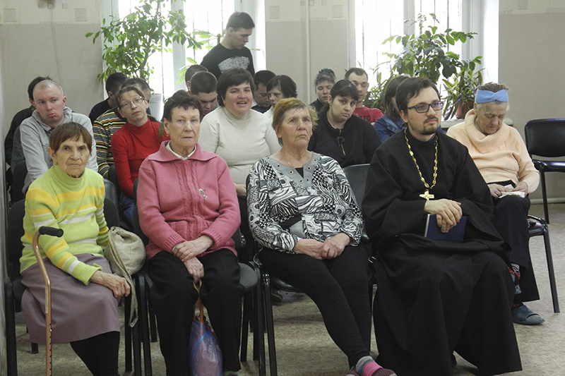 Аудитория и священник слушают рассказ библиотекаря.